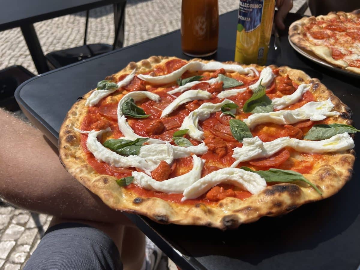 A pizza with red sauce, mozerella, and fresh basil