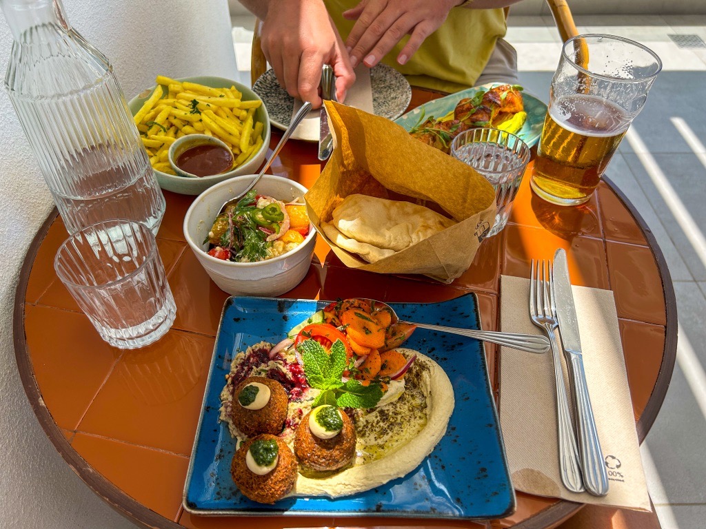 A lunch spread from Balagan with the Grand Balagan Mezze, chicken skewer, fries, and a tomato salad