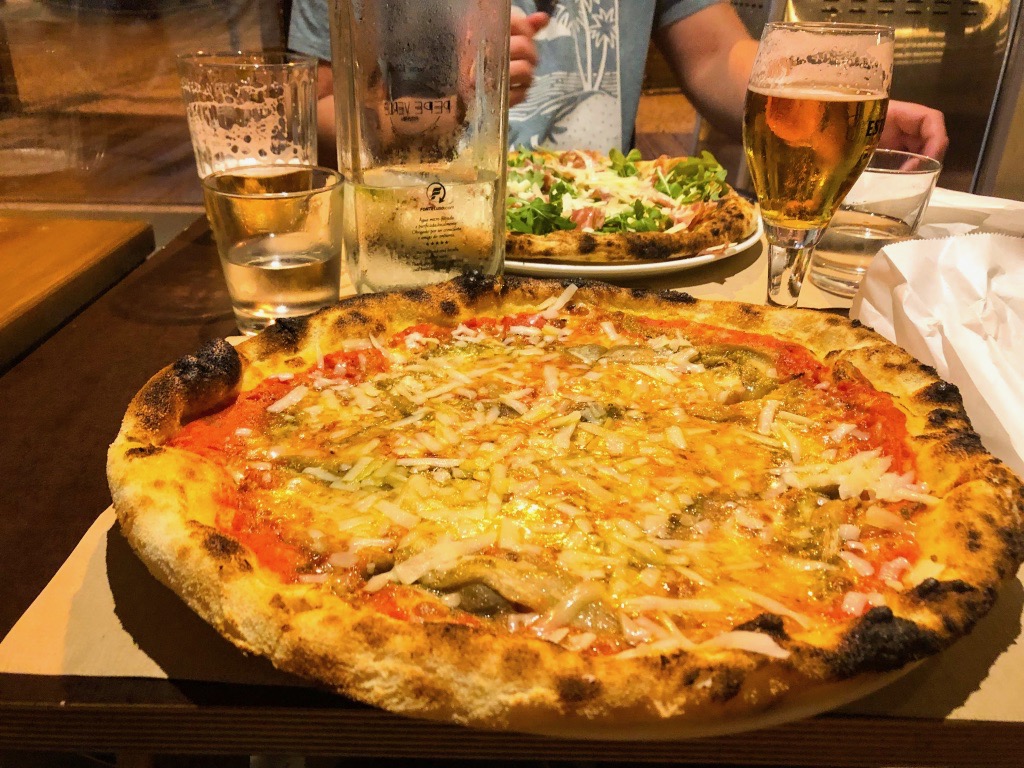 Two pizzas from Pepe Verde on a table with two beers
