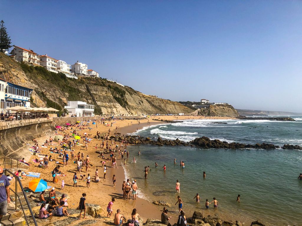 People swimming and sunbathing at Praia do Sul, Ericeira Beach.
